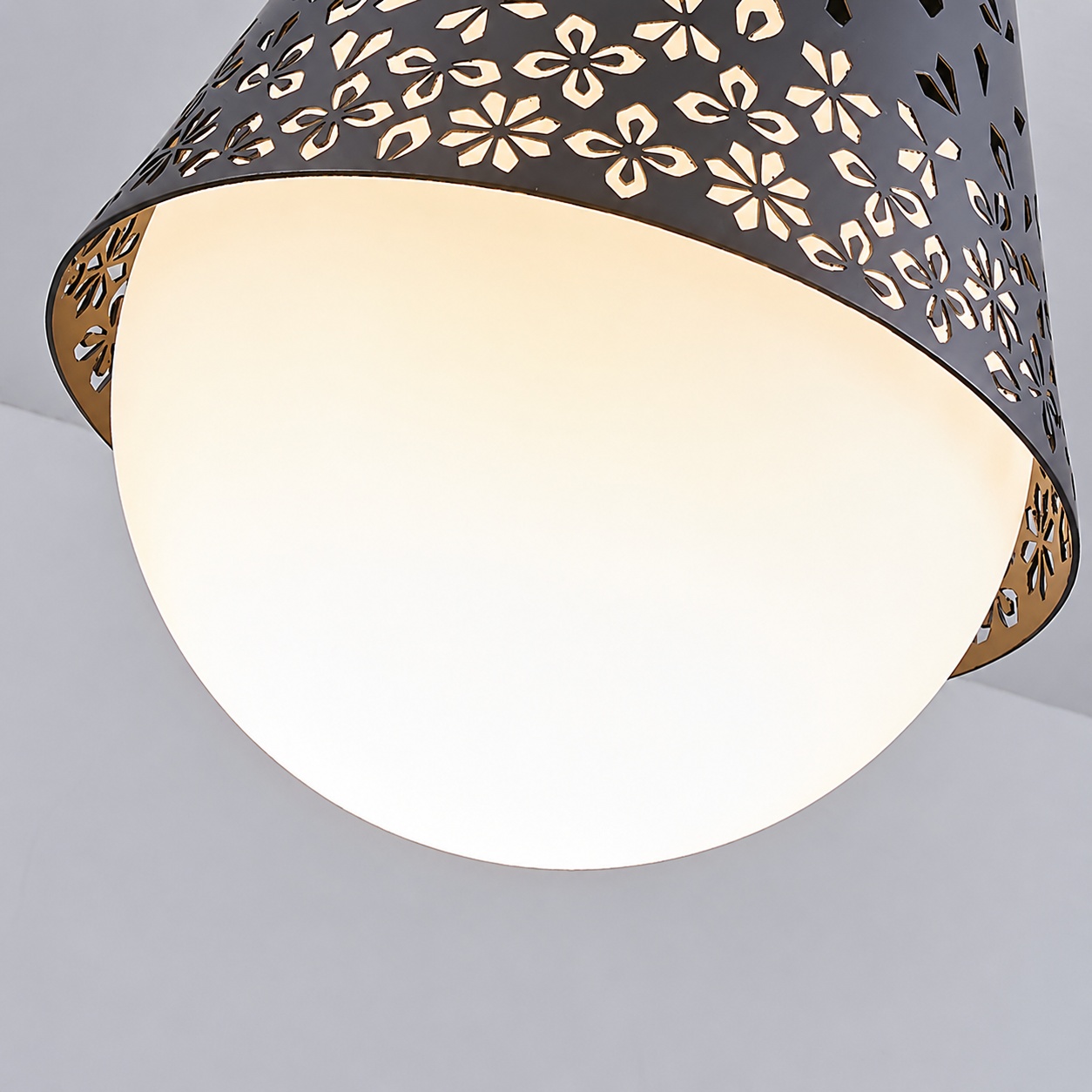 Close-up of perforated floral cutouts on the black metal pendant shade