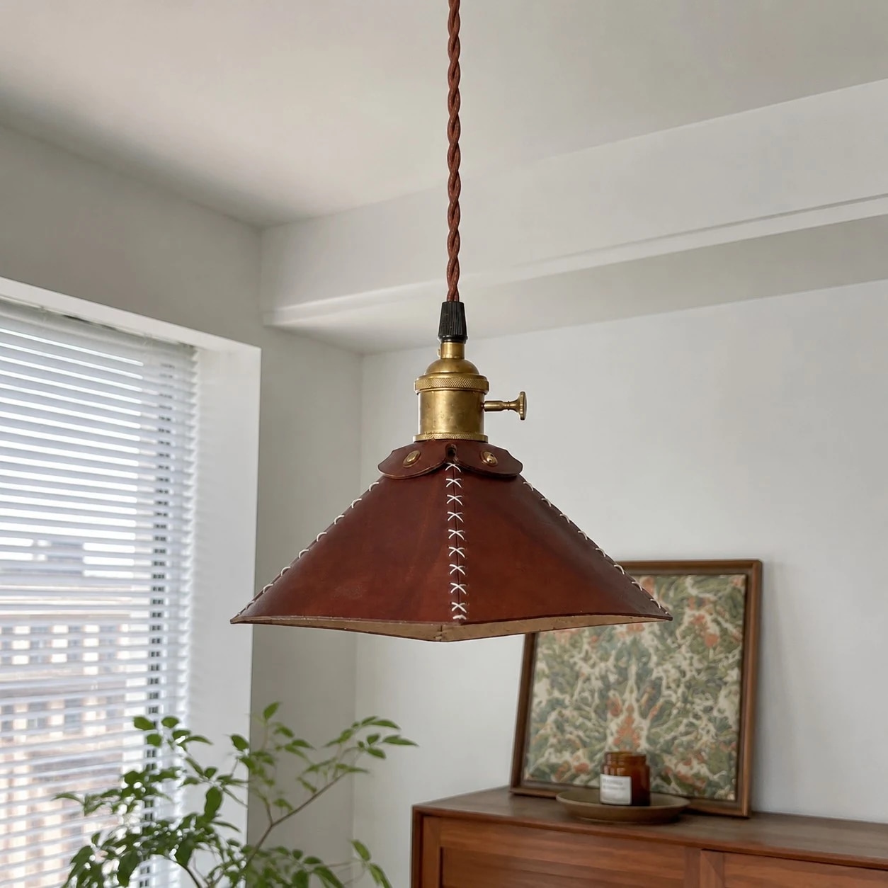 Leather pyramid pendant lamp above a sideboard by the window