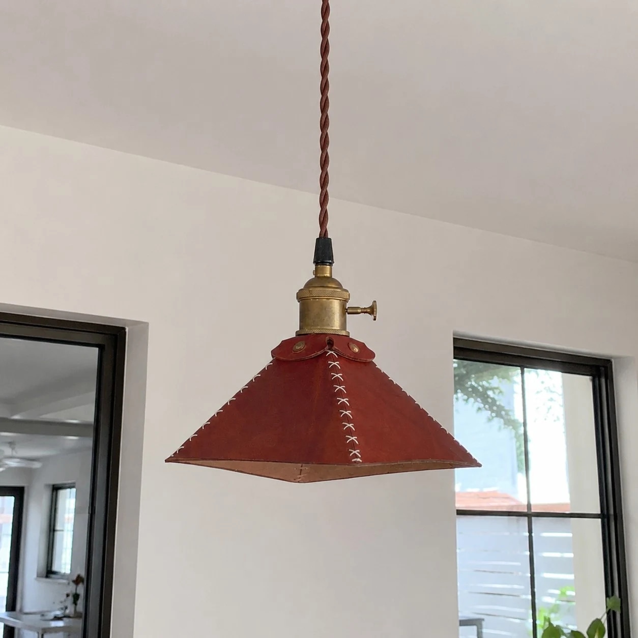 Leather pyramid pendant lamp hanging near a black framed window