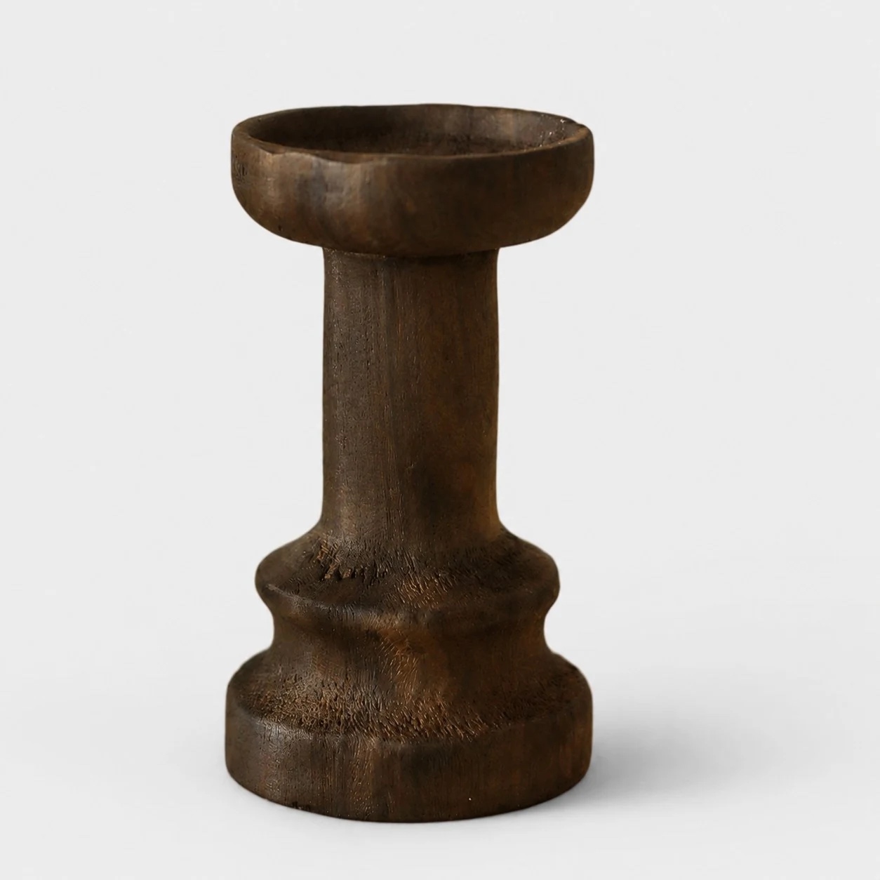 Tall dark solid wood candle holder on a neutral background
