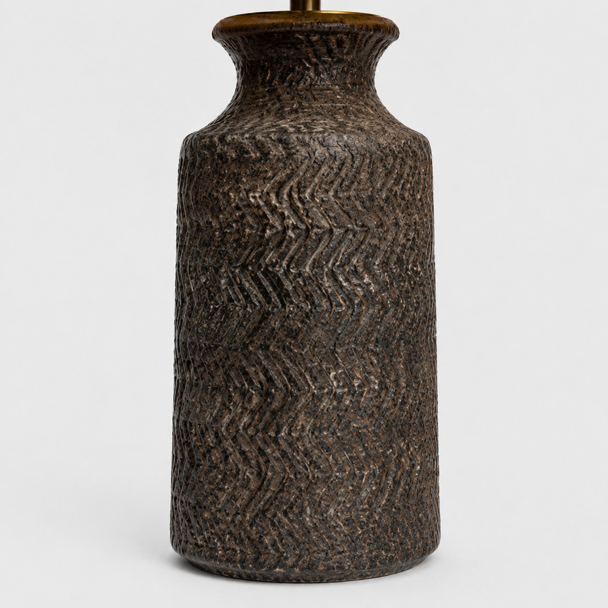 Close-up of carved wave texture on dark handmade ceramic lamp base